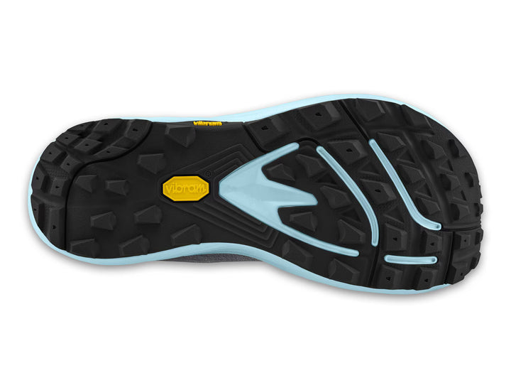 The image shows the black rubber outsole of the TOPO Pursuit 3 (Women’s) zero drop trail runner, featuring a blue border and a yellow Vibram logo. The Vibram Megagrip outsole displays rugged, multidirectional treads designed for optimal traction.