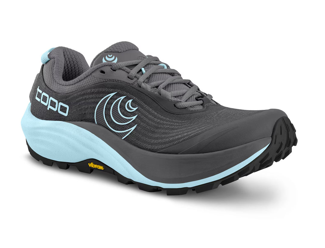 The TOPO Pursuit 3 (Women’s) is a gray and light blue trail running shoe featuring a mesh upper, cushioned platform, rugged black Vibram Megagrip outsole, and TOPO branding on the side and tongue.
