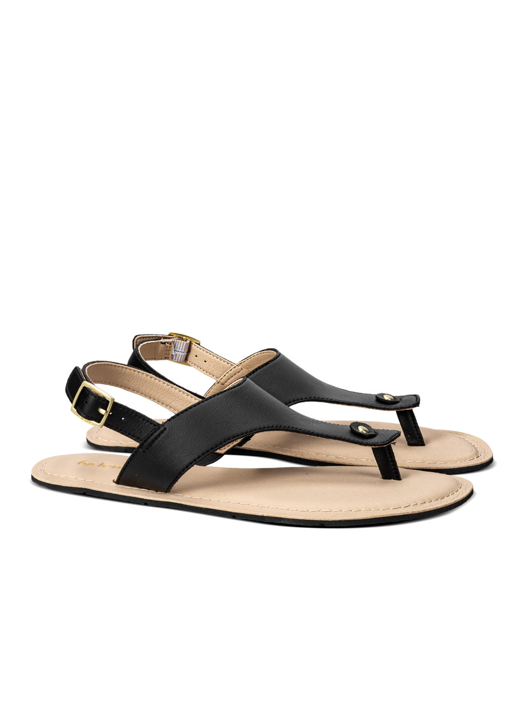 A pair of BeLenka Promenade 2.0 (Women's) black leather thong barefoot sandals with a beige footbed, an elegant strap featuring a gold buckle at the ankle, and flat soles, displayed against a white background.