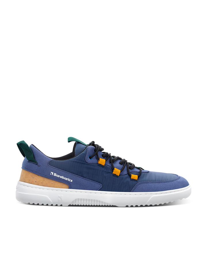 The Barebarics Revive (Men's) is a navy blue and white low-top sneaker with black laces, orange lace loops, green pull tabs, a tan heel accent, and "Barebarics" on the side—designed for barefoot comfort.