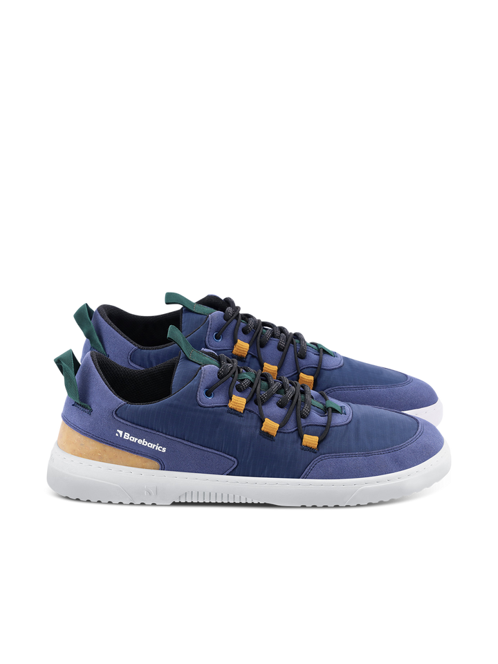 The Revive (Men's) by Barebarics is a casual sneaker featuring blue uppers, yellow accents, green pull tabs, black laces, and white soles. Made from vegan materials, these lightweight shoes offer barefoot comfort for everyday wear.