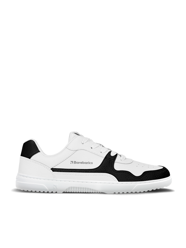 The Barebarics Zing (Unisex) sneakers feature a modern black and white low-top design with laces, the Barebarics logo on the side, a white sole, and are crafted from sustainable leather, all shown on a plain white background.