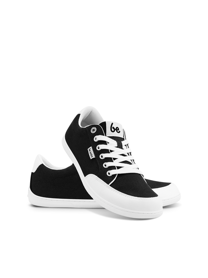 A pair of BeLenka Rebound (Unisex) black and white retro sneakers with white laces and soles are shown on a white background—one upright with the "be" label visible on the tongue, the other leaning against it. Comfortable and stylish.