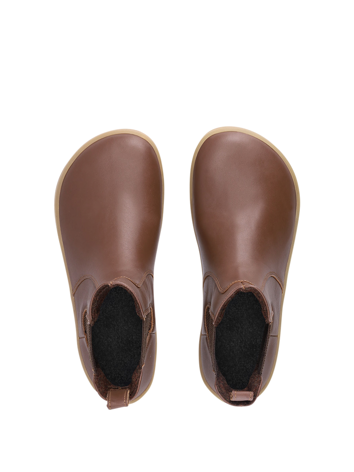 A pair of BeLenka Entice Neo (Unisex) brown slip-on barefoot boots with a wide toe box and rounded toes, featuring black inner lining and elastic side panels, shown from above on a white background.