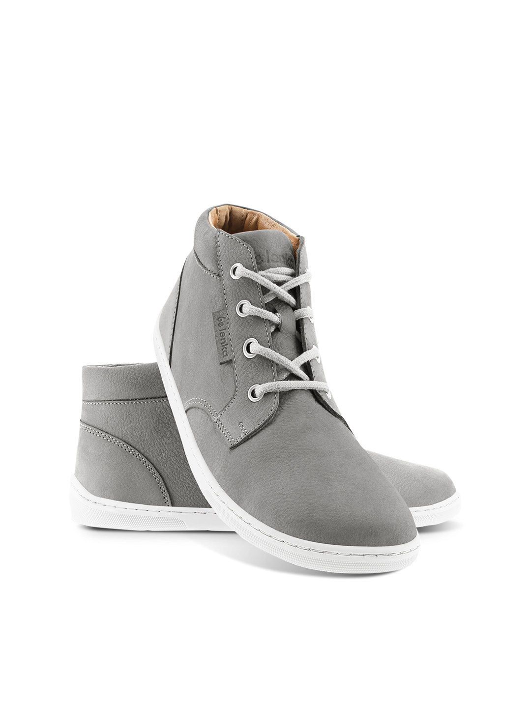 The BeLenka Synergy (Unisex) barefoot shoes are shown in gray with a wide toe-box, white soles, and white laces on a white background. One shoe stands upright while the other lies on its side behind it.