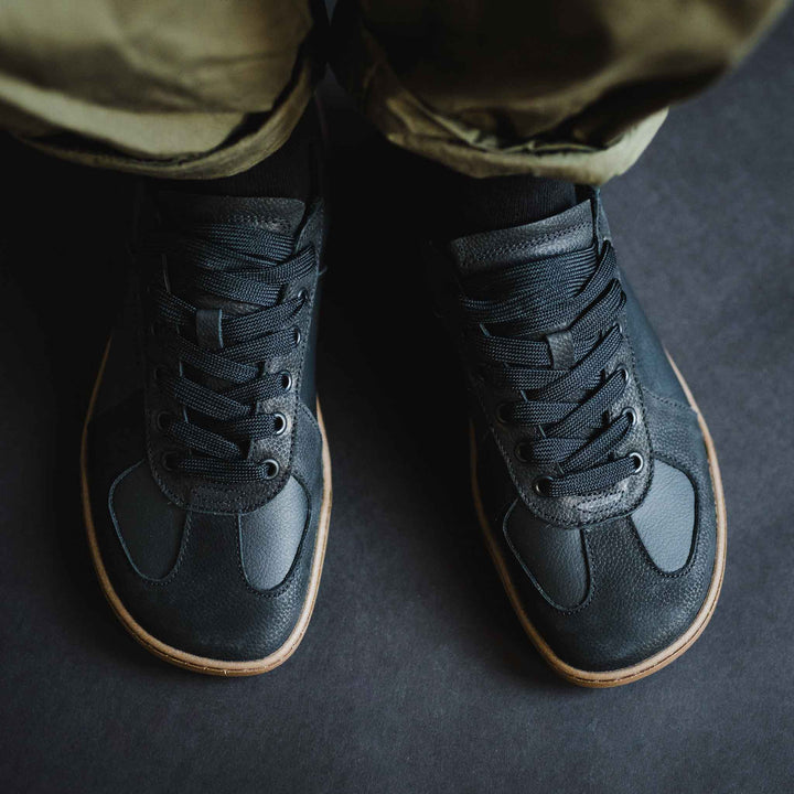 A top-down view of a person wearing BluSun BLSN-200 men’s shoes with gum soles and olive green pants, standing on a dark surface.