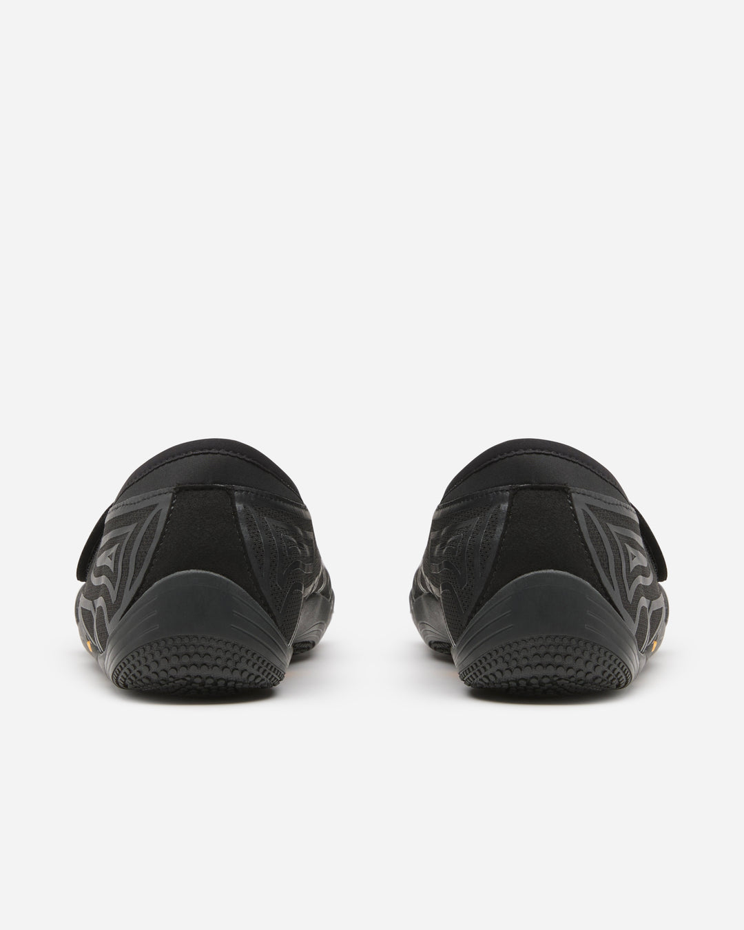 Back view of Vibram Groundsplay (Women's) black slip-on shoes with subtle geometric patterns and textured soles for circuit training, shown on a white background.