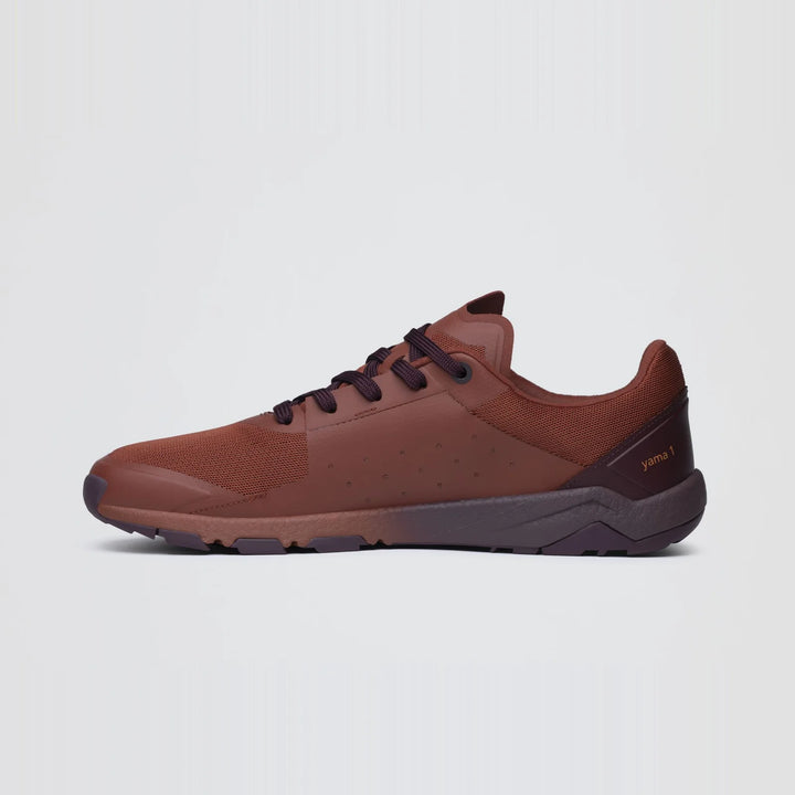 The Notace Yama T1 (Men’s) is a brown trail shoe featuring a low profile, black laces, and a black sole, engineered for all-day comfort; it is presented in a side view against a plain white background.